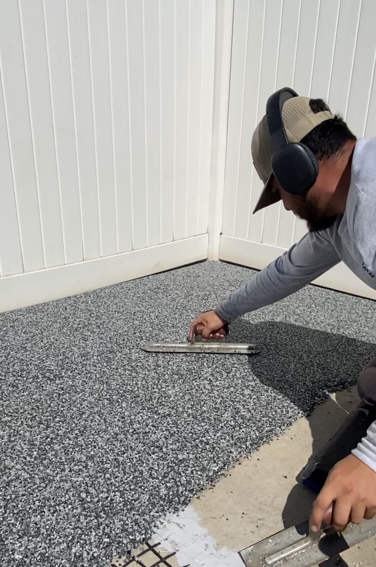 Installer hand-troweling gray Vuba Stone over an existing concrete slab
