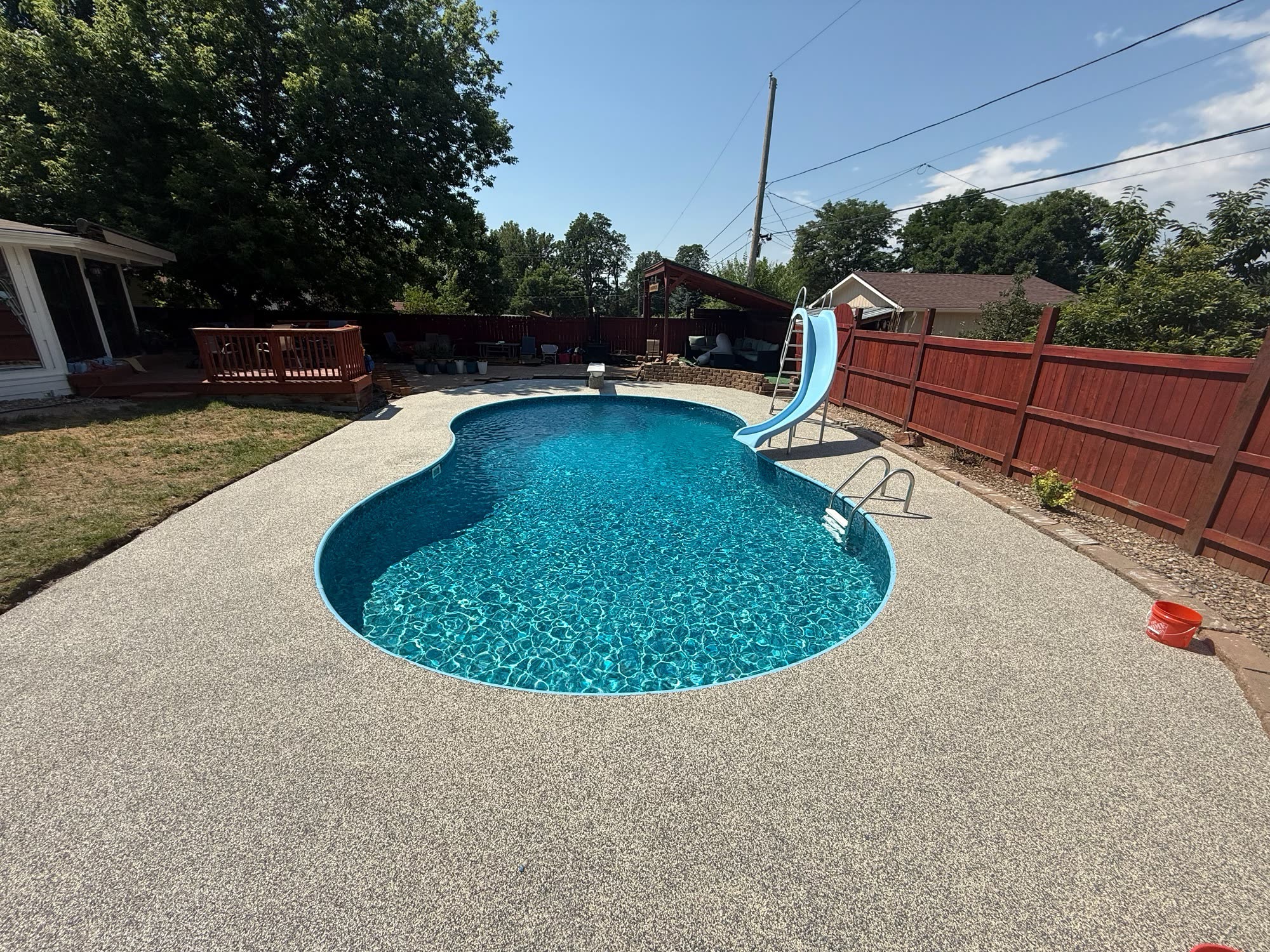 Kidney-shaped backyard pool surrounded by a light Vuba Stone pool deck